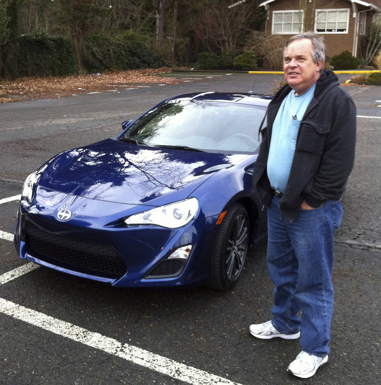 In this 2013 photo, Alan Naiman poses with his new car, an unusual extravagance for him, in Seattle. (Shashi Karan via AP)