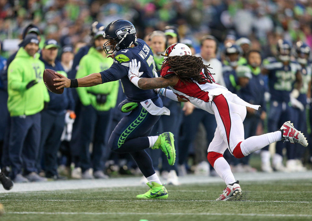 Seattle’s Russell Wilson puts his arm out to get a first down as Arizona’s Tre Boston shoves him out of bounds during the Seahawks’ 27-24 win over Arizona on Sunday at CenturyLink Field in Seattle. (Andy Bronson / The Herald)
