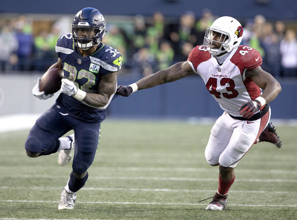 Seattle’s Chris Carson runs past Arizona’s Haason Reddick during the Seahawks’ 27-24 win over Arizona on Sunday at CenturyLink Field in Seattle. (TJ Mullinax / For the Herald)
