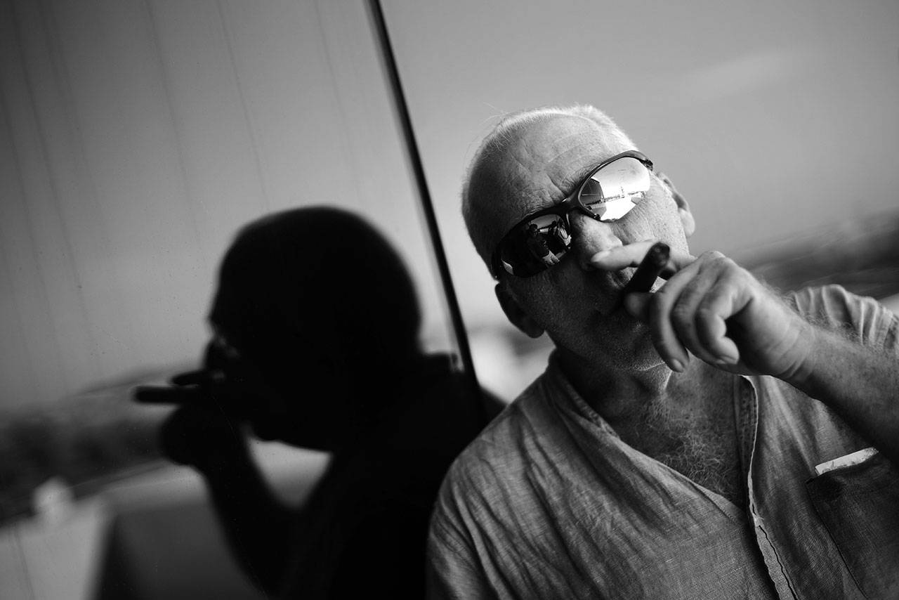This Feb. 27, 2017, photo shows Associated Press photojournalist Desmond Boylan smoking a cigar on the balcony of the agency’s office in Havana, Cuba. Boylan, a photographer who covered war and conflict across the world before dedicating his life to documenting the joys and tribulations of daily life in Cuba for The Associated Press, died suddenly Saturday afternoon in Havana. He was 54. (AP Photo/Ramon Espinosa)