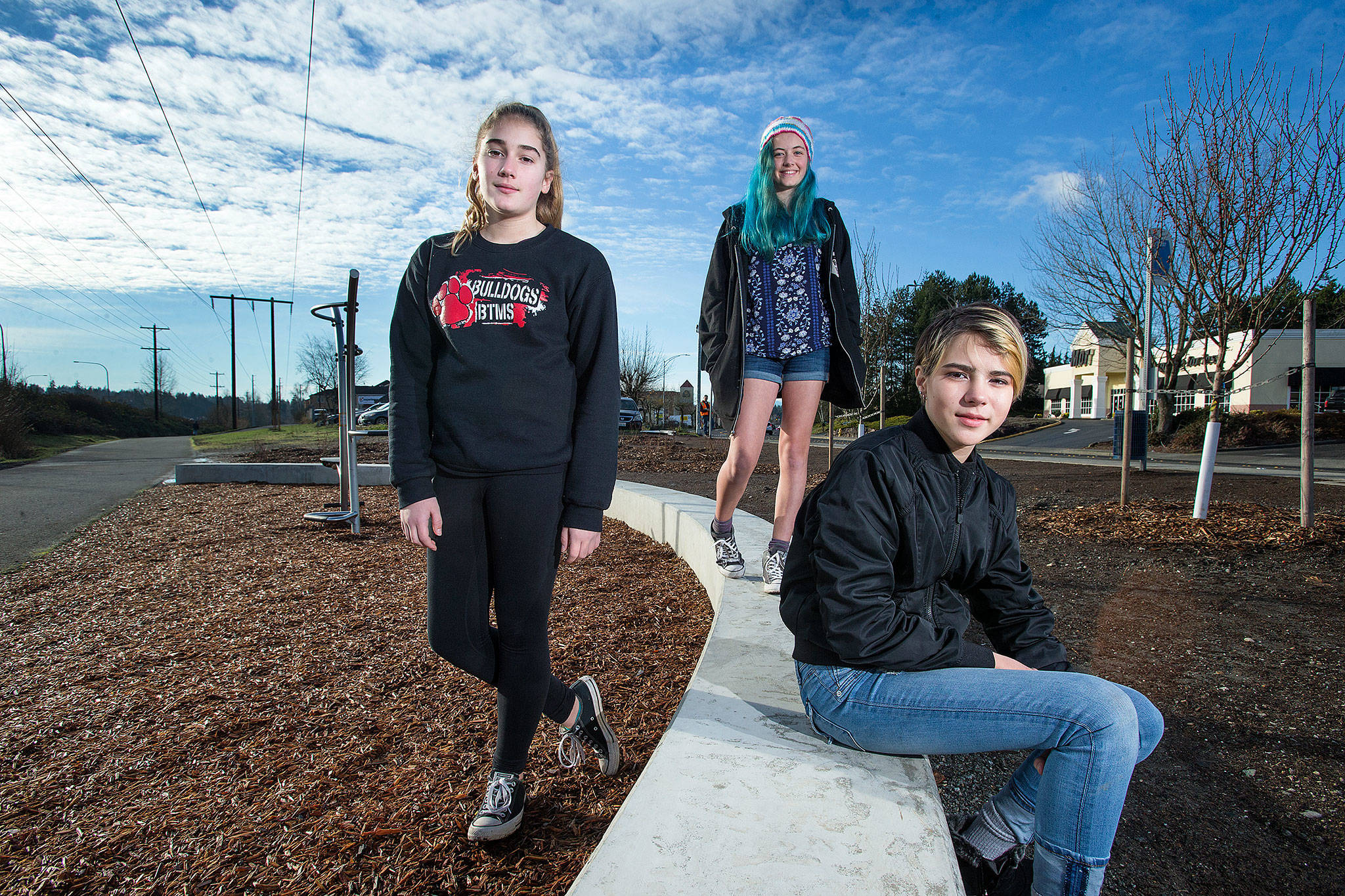From left, Lindsey Gard, Penny Campbell and Inanna Liaw pose in a landscaped area of the Interurban Trail in Lynnwood, where they planted blueberries and put down padding under fitness equipment for their Silver Award project. The three belong to Girl Scout Troop 41246. (Andy Bronson / The Herald)