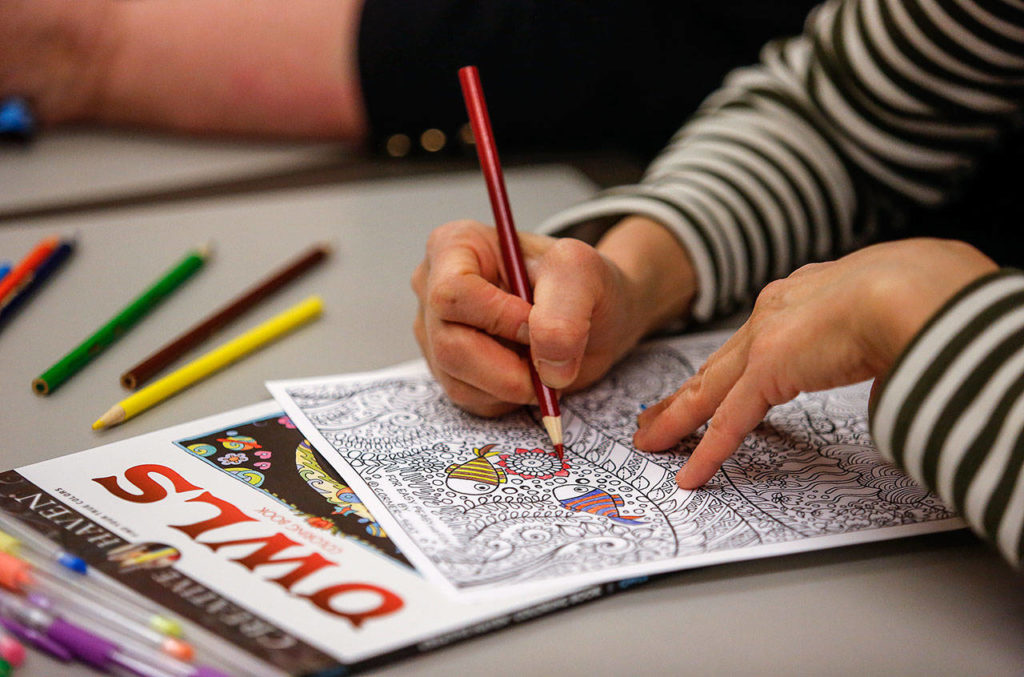 Wai Ng, 59, colors a highly detailed drawing at the Everett Public Library’s Coloring and Conversation Wednesday evening. (Dan Bates / The Herald)
