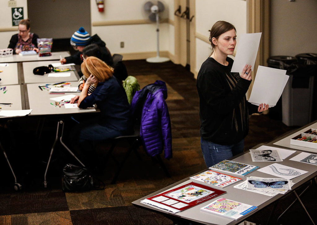 Desiree Boss, 26, looks through materials available to her before selecting something to color. (Dan Bates / The Herald)
