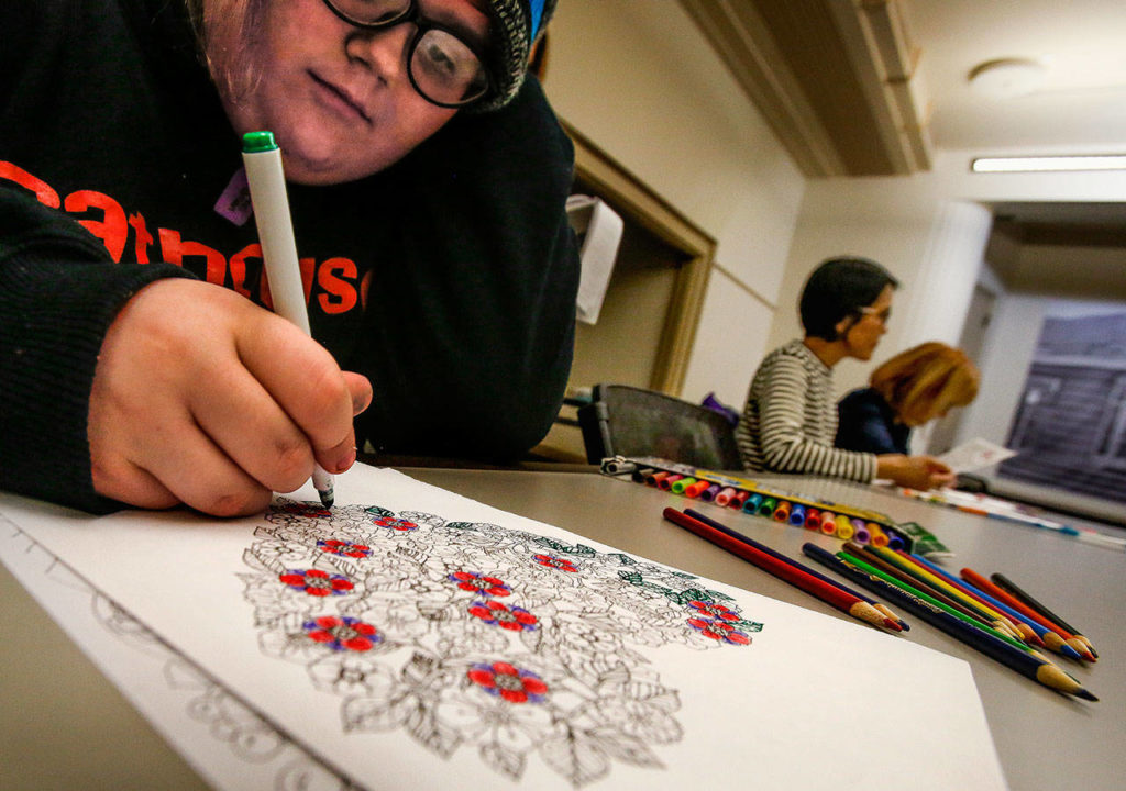 Jaiden Boss, 14, colors a printed drawing with ornaments from a Christmas book Wednesday at the library’s Coloring and Conversation. (Dan Bates / The Herald)
