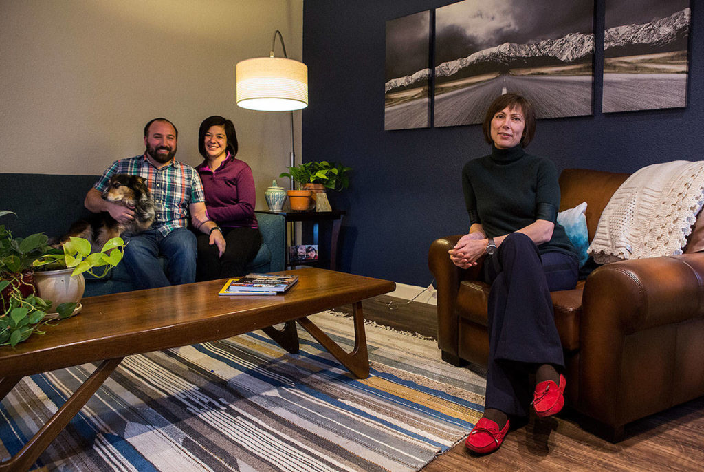 Cam Stefanic and Kari Logan (center) sit in their living room designed by Katerina Bolshakova (right) with a ski resort theme. (Olivia Vanni / The Herald)

