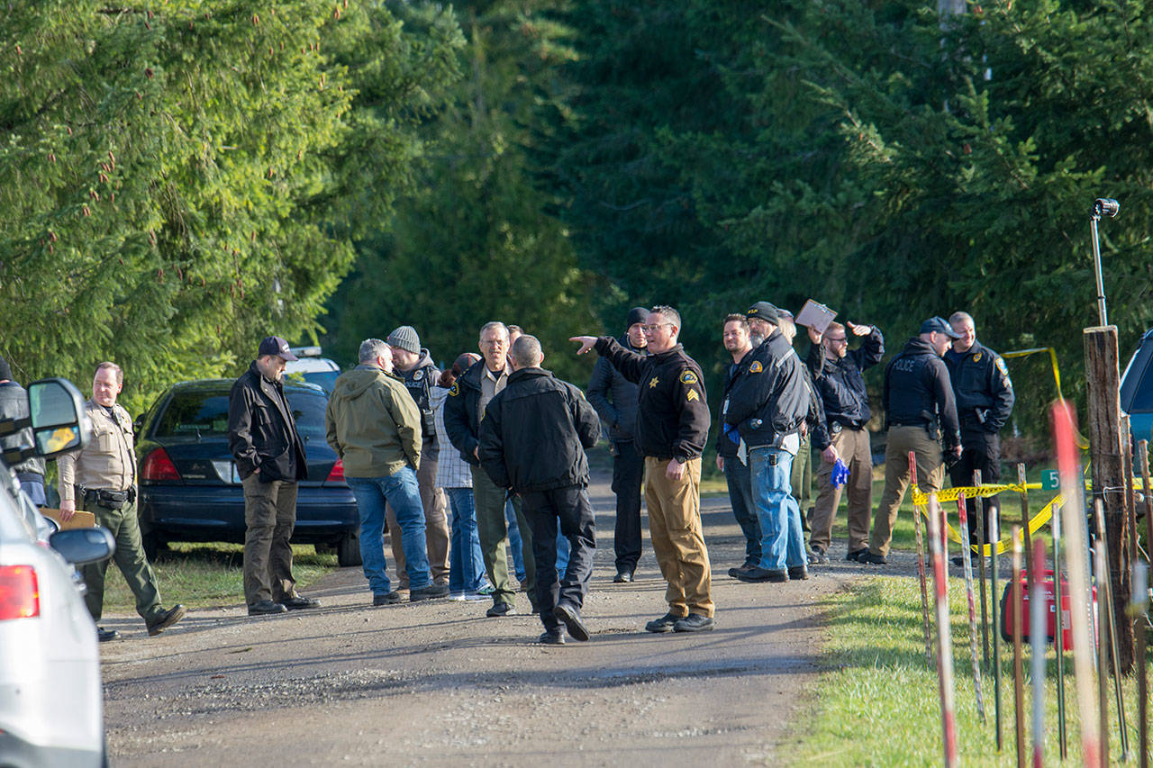 Investigators are seen Tuesday at a property on Bear Meadow Road near Port Angeles where three bodies have been found. (Jesse Major / Peninsula Daily News)