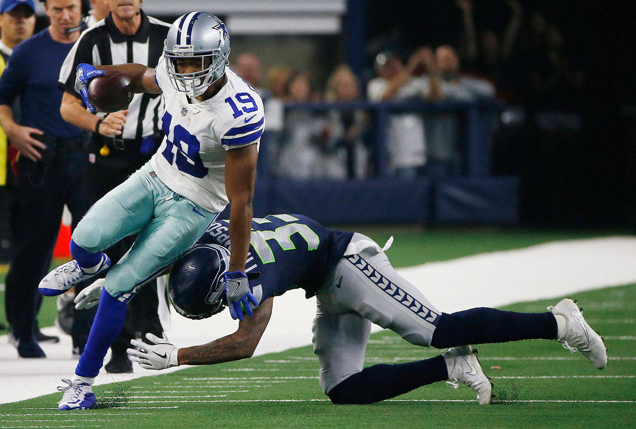 Dallas’ Amari Cooper is hit by Seattle’s Tedric Thompson during the first half of Saturday’s game in Arlington, Texas. (Ron Jenkins / Associated Press)