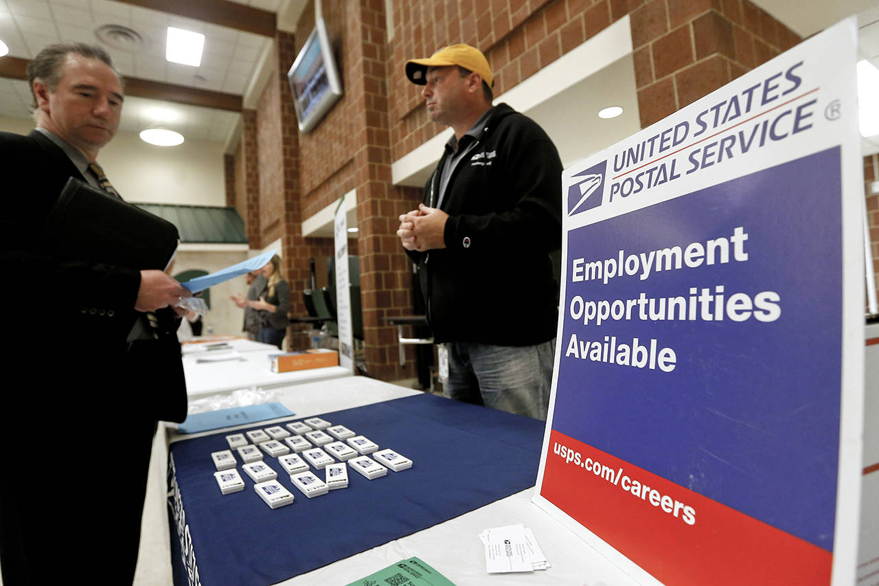 In this 2017 photo, a recruiter from the postal service (right) speaks with an attendee of a job fair in the cafeteria of Deer Lakes High School in Cheswick, Pennsylvania. (AP Photo/Keith Srakocic, File)
