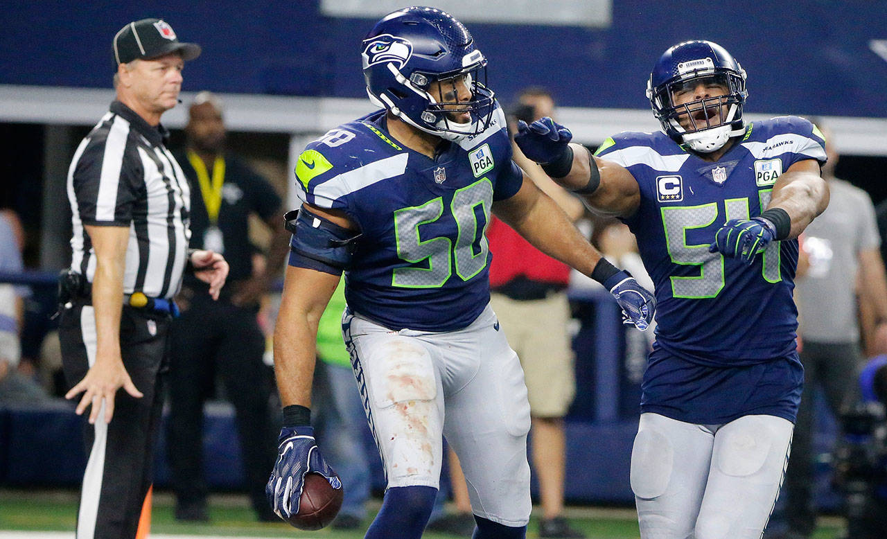 The Seahawks’ K.J. Wright (50) and Bobby Wagner (54) celebrate Wright’s interception during a playoff game against Dallas on Jan. 5, 2019, in Arlington, Texas. (AP Photo/Michael Ainsworth)