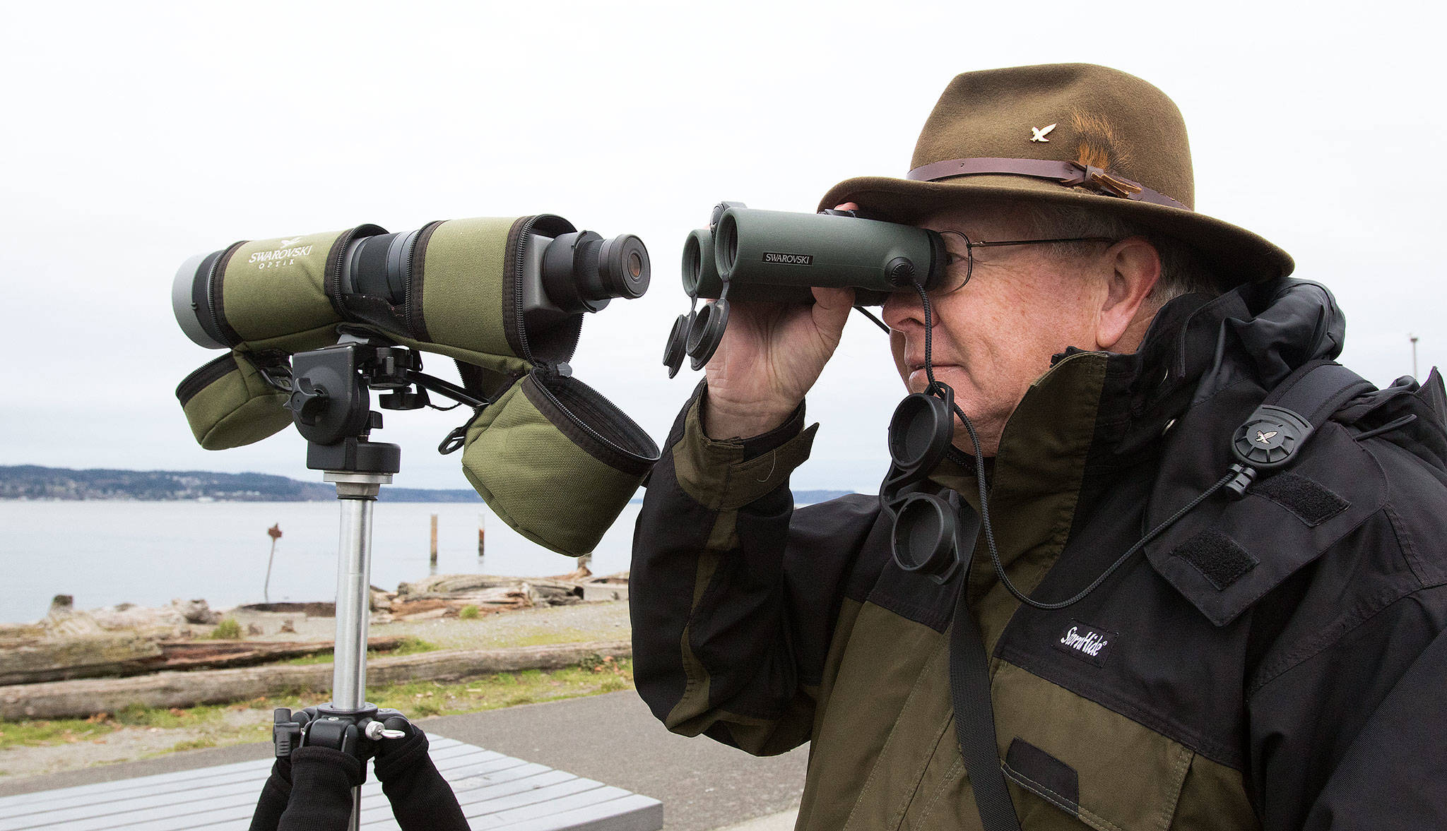 Rick Taylor switches to binoculars to look at birds in the waters by the Mukilteo Lighthouse Park on Tuesday, Jan. 8, 2019 in Mukilteo, Wa. (Andy Bronson / The Herald)