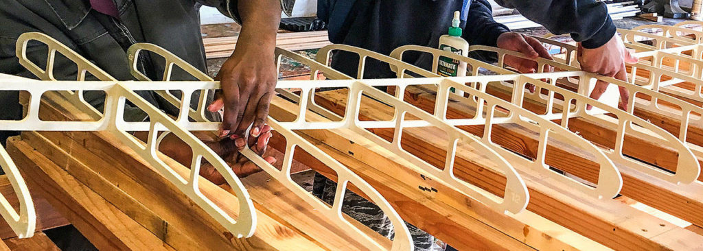 Taking instruction from Calvin Nichols, court-involved kids with Snohomish County Juvenile Court’s Youth Enrichment Services glue intricate parts of the custom paddleboard’s frame together. (Contributed Photo)
