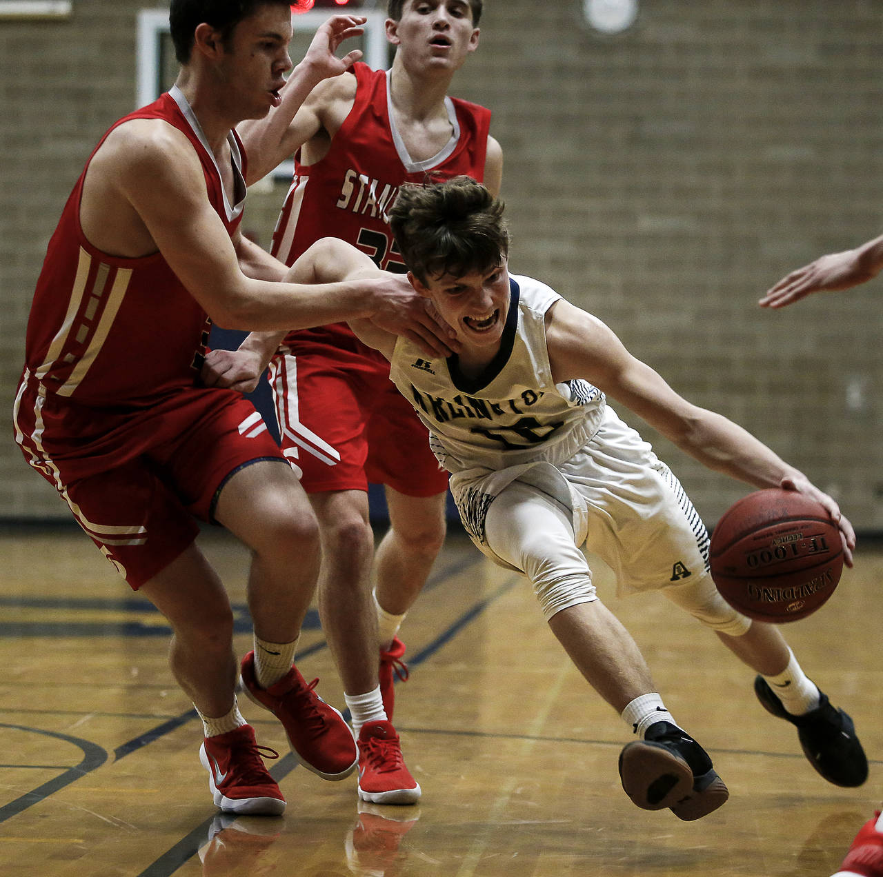 Arlington’s Anthony Whitis (right) drives to the basketball during a game last season against Stanwood. (Ian Terry / The Herald)