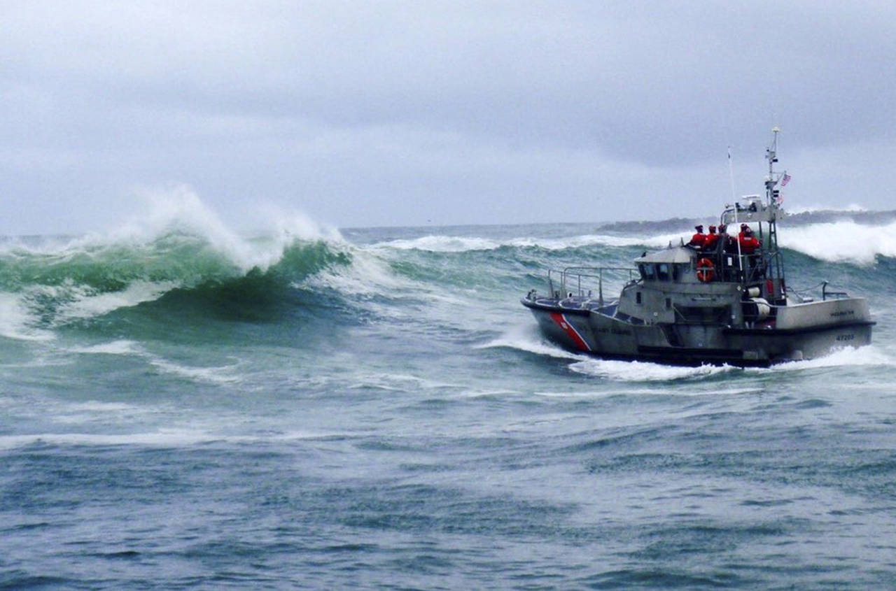 In this Tuesday photo, a U.S. Coast Guard boat crew responds to three fishermen in the water after the commercial fishing vessel Mary B II capsized while crossing Yaquina Bay Bar off the coast of Newport, Oregon. (U.S. Coast Guard via AP)