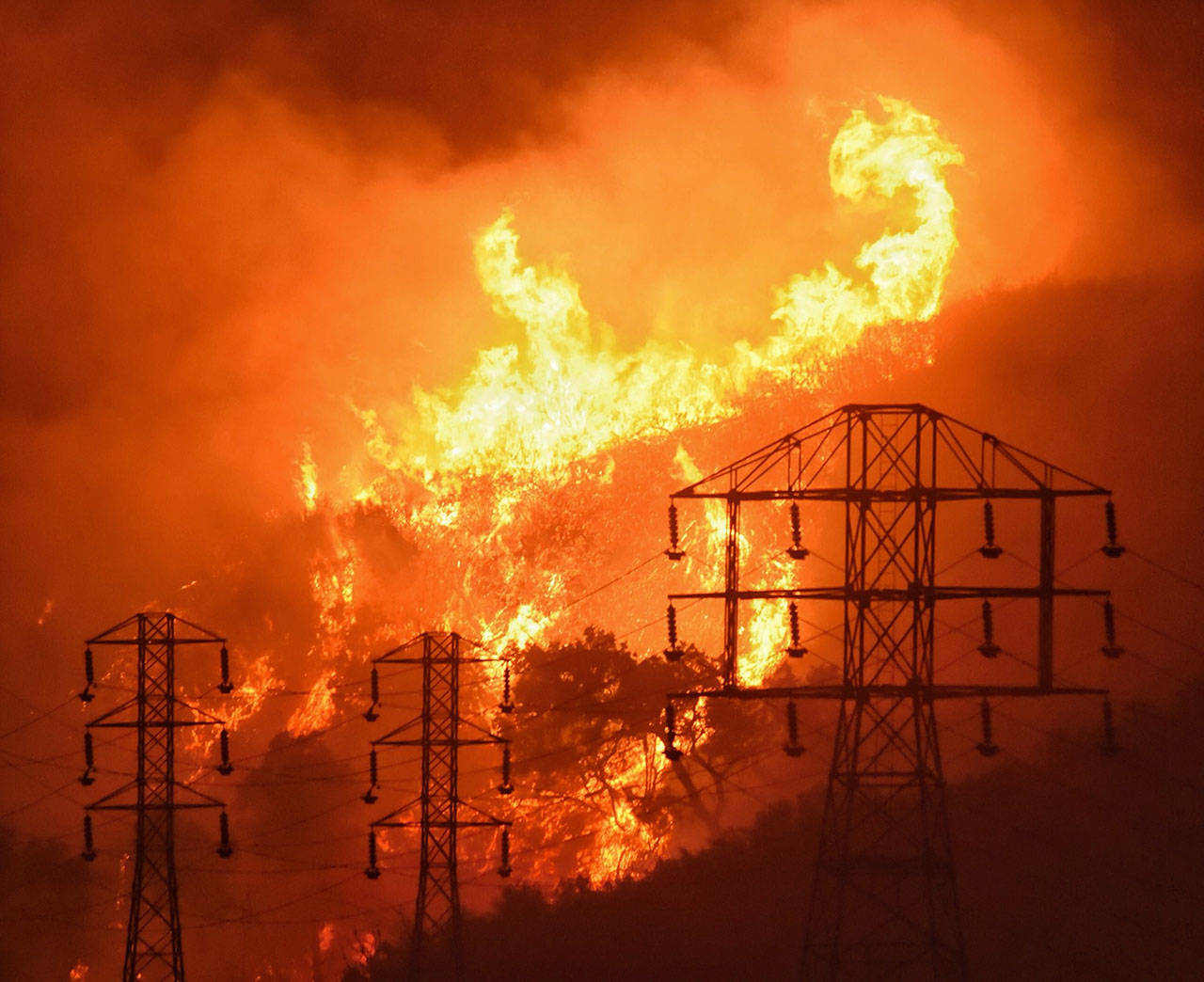 In this 2017 photo, flames burn near power lines in Sycamore Canyon near West Mountain Drive in Montecito, California. (Mike Eliason/Santa Barbara County Fire Department via AP, File)