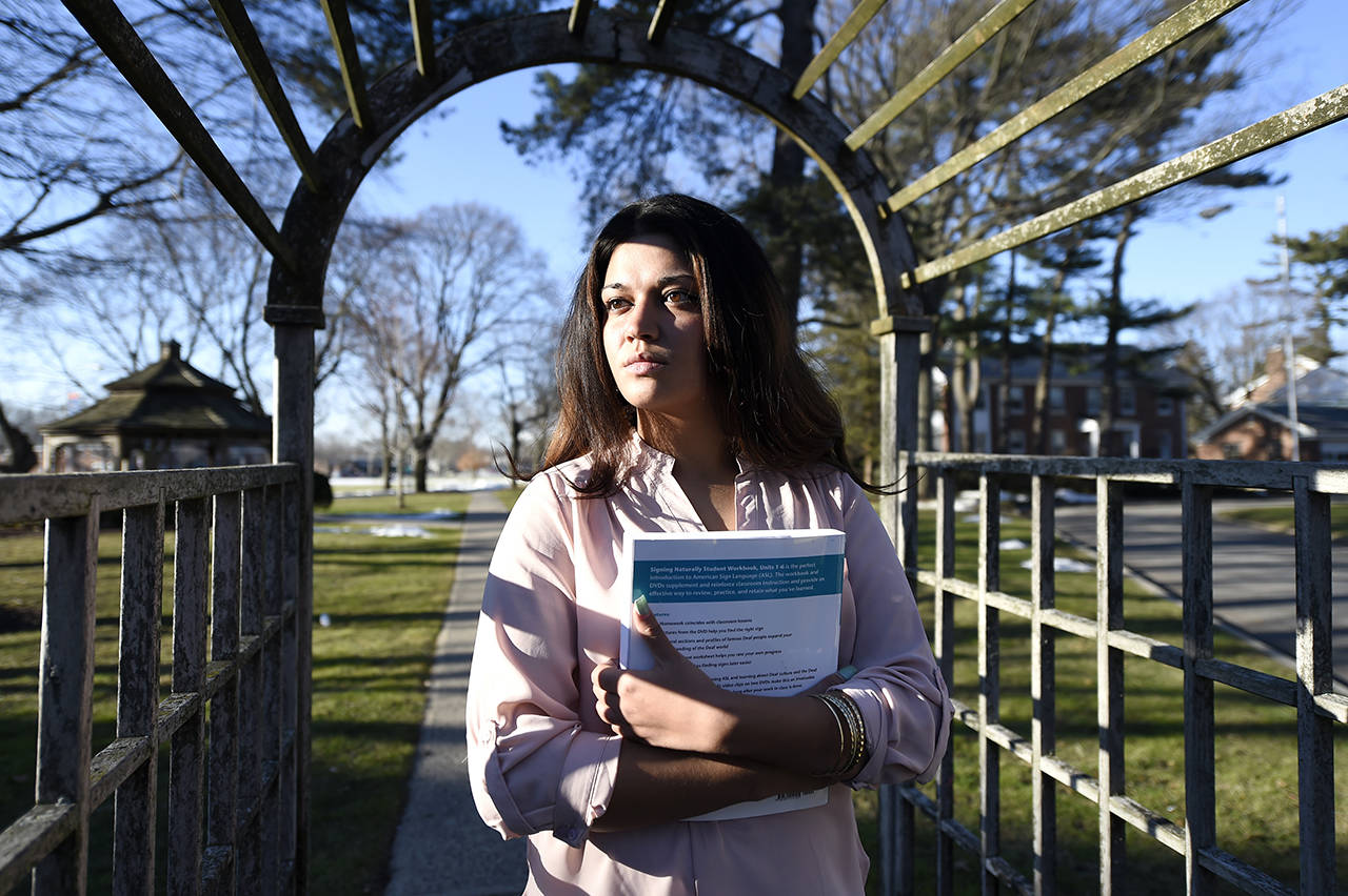 In this 2016 photo, Naila Amin, 26, holds a book from one of the classes she was taking at Nassau Community College in Garden City, New York. “My passport ruined my life,” said Amin, a dual citizen from Pakistan who grew up in New York City. She was forcibly married at 13 in Pakistan and applied for papers for her 26-year-old husband to come to the country. (AP Photo/Kathy Kmonicek)