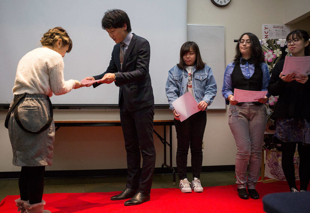 Takayuki Ishikawa, with the Consulate-General of Japan in Seattle, hands certificates to participants of the Coming of Age ceremony at Everett Community College. (Olivia Vanni / The Herald)
