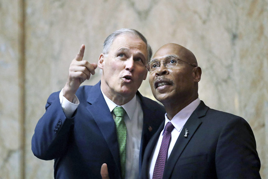 Gov. Jay Inslee (left) talks with Rep. John Lovick, D-Mill Creek, following Inslee’s State of the State address to a joint session of the Legislature on Tuesday in Olympia. (AP Photo/Elaine Thompson)
