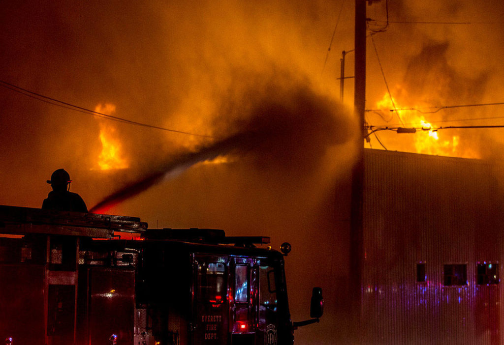 A Everett firefighter sprays water on the Judd & Black appliance store at 3001 Hewitt Ave that burned on Sept. 21, 2018, in Everett. (Olivia Vanni / Herald file)
