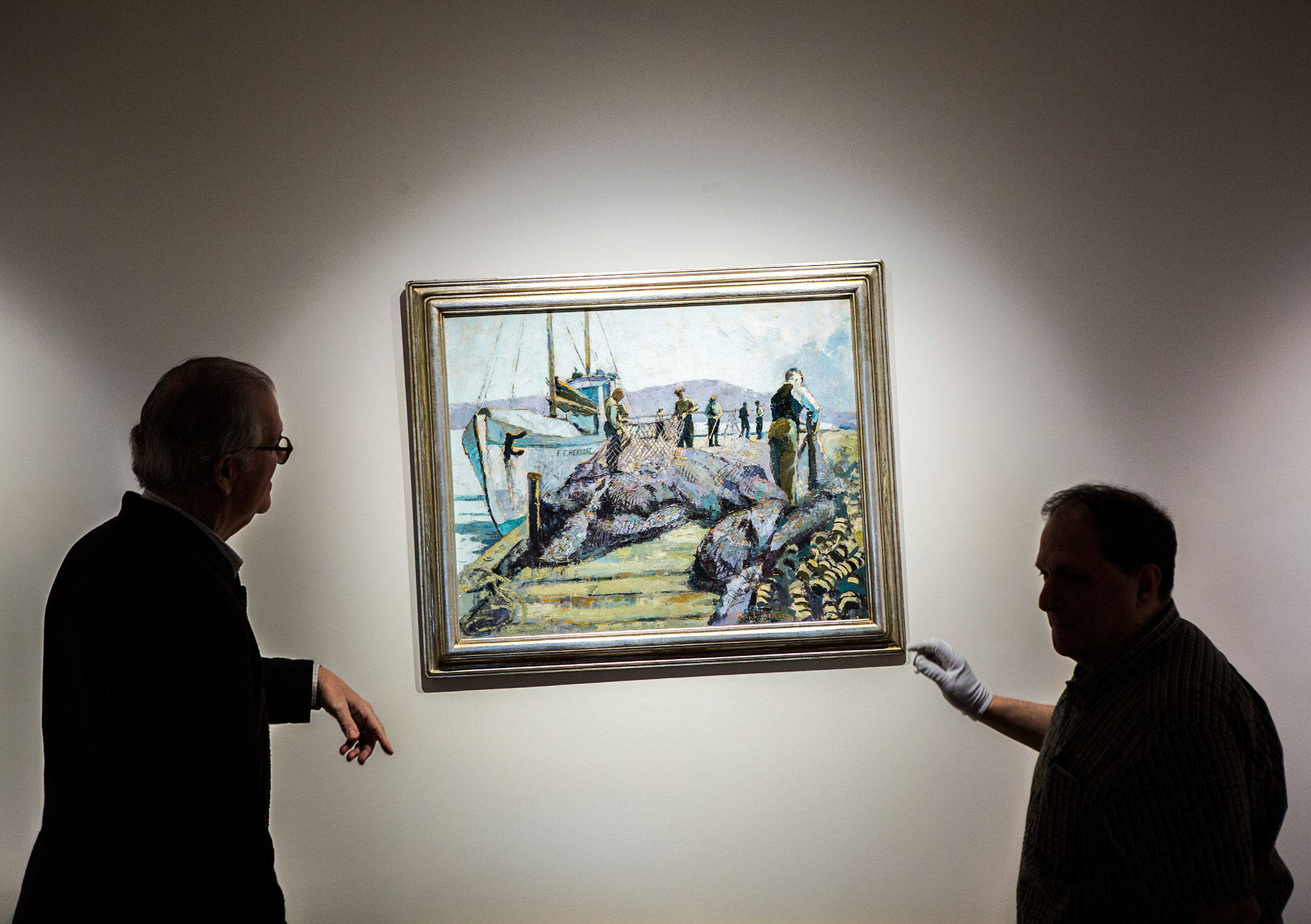 Lindsey Echelbarger, president of the Cascadia Art Museum, left, and curator David Martin, right, adjust a painting at the Cascadia Art Museum in Edmonds. (Olivia Vanni / The Herald)