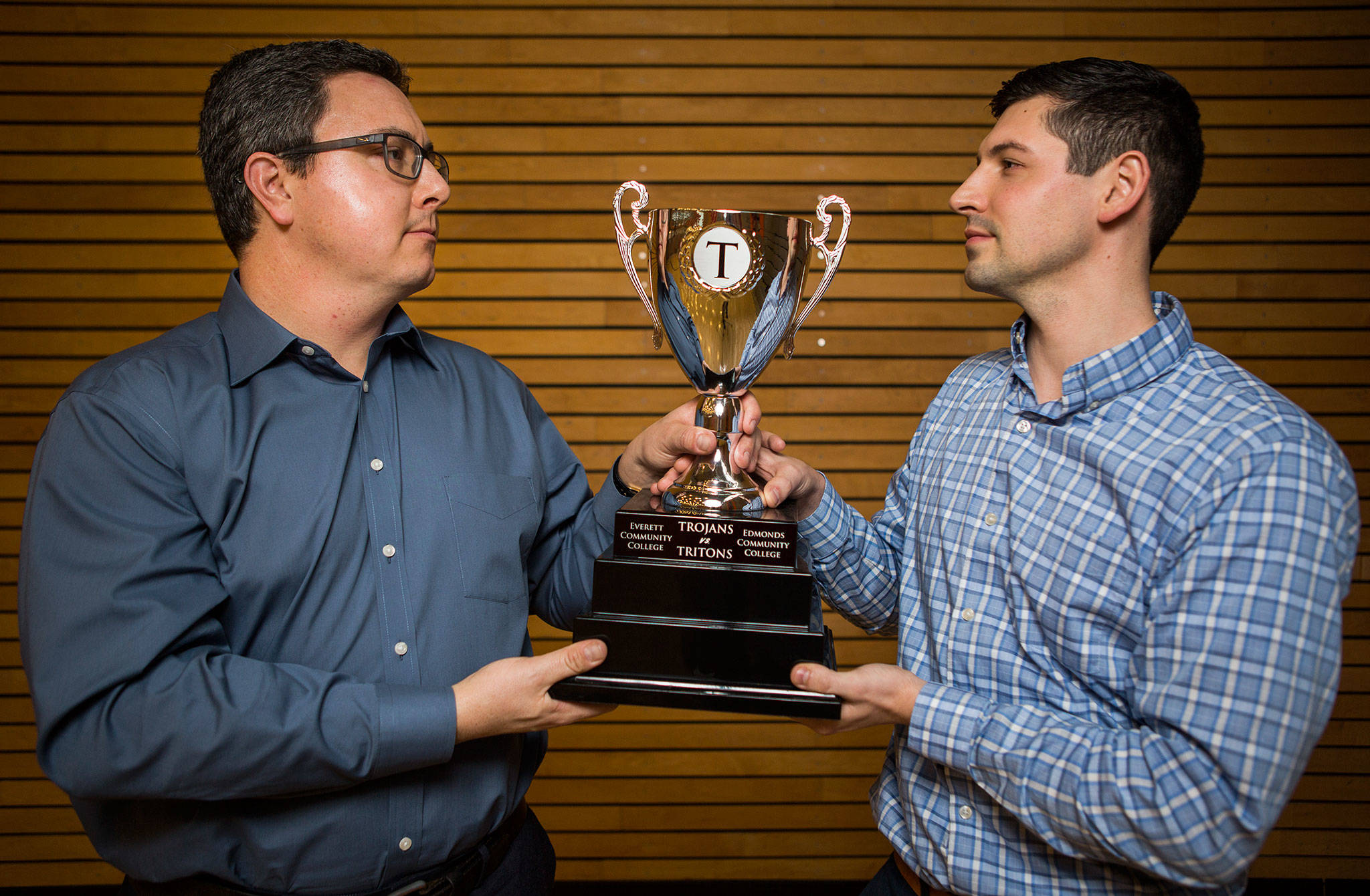 Edmonds Community College athletic director Spencer Stark (left) and Everett Community College athletic director Garet Studer hold the “T” Trophy at Everett Community College on Thursday. (Olivia Vanni / The Herald)
