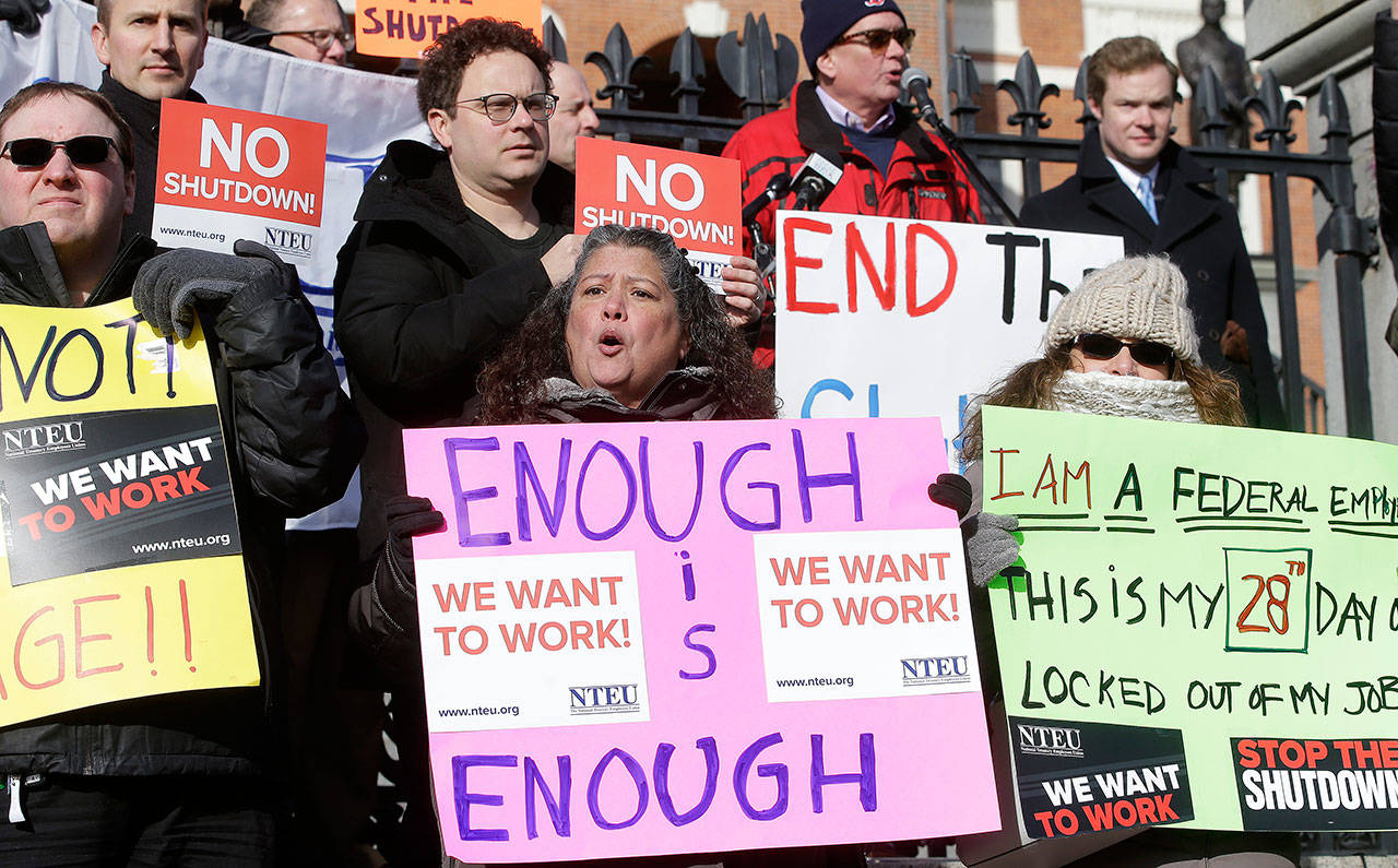 Internal Revenue Service employees (front row from the left) Brian Lanouette, of Merrimack, New Hampshire, Mary Maldonado, of Dracut, Massachusetts, and Maria Zangari, of Haverhill, Massachusetts, display placards during a rally by federal employees and supporters Thursday in front of the Statehouse in Boston. (AP Photo/Steven Senne)