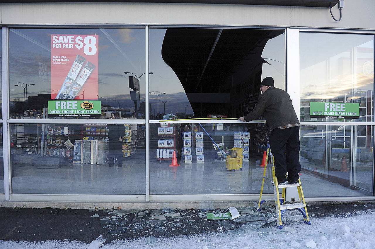 In this Nov. 30, 2018 photo, Dennis Keeling, of Instant Services, measures for a broken window at an auto parts store following an earthquake in Anchorage, Alaska. (AP Photo/Mike Dinneen, file)