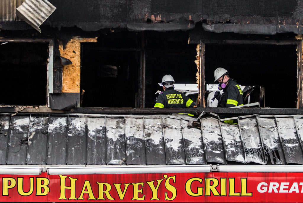 Investigators with the Everett Fire Department inspect the top floor of Harvey’s Pub on Broadway on Sunday after a fatal fire. (Olivia Vanni / The Herald) 
