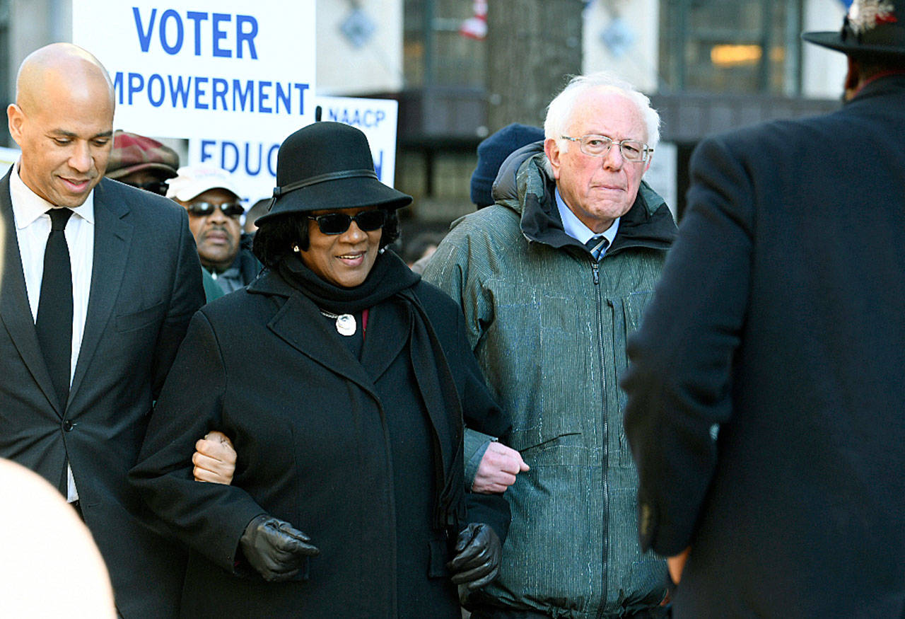Following a Martin Luther King Jr. prayer service Monday at Zion Baptist Church in Columbia, South Carolina, New Jersey Sen. Cory Booker, D-New Jersey (left) and Sen. Bernie Sanders, I-Vermont., walk with NAACP President Brenda Murphy during a march to the Statehouse. (AP Photo/Meg Kinnard)