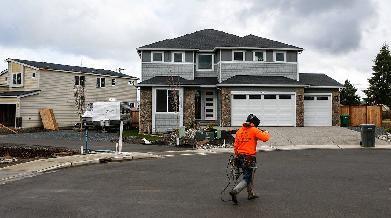 A construction worker walks by houses under construction in a cul-de-sac on 8th Place SE on Wednesday, March 8, 2017, in Lake Stevens, Wa. (Ian Terry / The Herald)