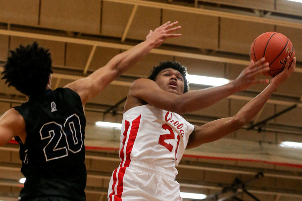 Marysville Pilchuck’s RaeQuan Battle (right) attempts a shot around the outstretched arm of Arlington’s Will Abram during a Wesco 3A boys basketball game Wednesday in Marysville. (Kevin Clark / The Herald)
