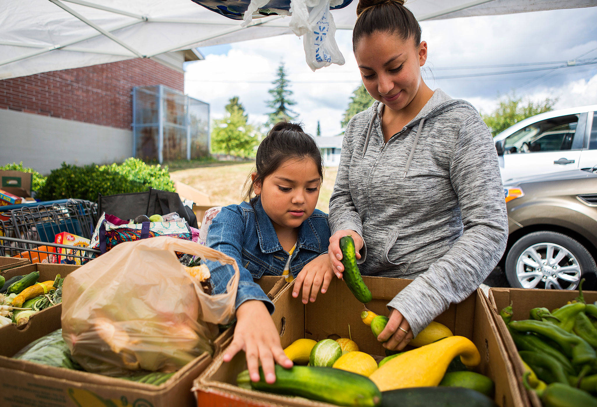Anna Granados and daughter Alaisa Granadaos, 7, look through a box of vegetables at the Lake Stevens Community Food Bank in August in Lake Stevens. The partial government shutdown has increased use of food banks in Snohomish County and donations are needed to help meet that need. (Olivia Vanni / Herald file photo)