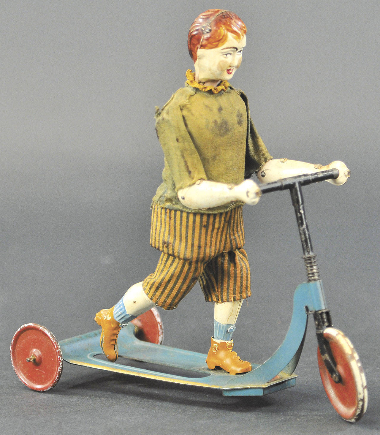 The young red-headed boy on a scooter toy is made of metal, but he is dressed in a cloth suit. It was made by Victor Bonnet soon after World War I and is priced at $1,560. (Cowles Syndicate Inc.)