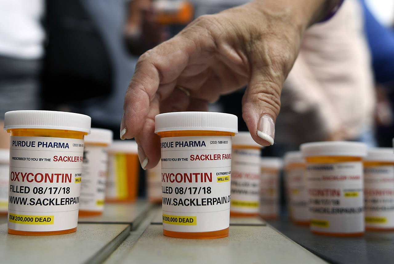 Family and friends who have lost loved ones to OxyContin and opioid overdoses leave pill bottles in protest outside the headquarters of Purdue Pharma, which is owned by the Sackler family, on Aug. 17, 2018, in Stamford, Conn. The Snohomish County Council voted to pursue a lawsuit against Purdue Pharma and distributor McKesson Pharmaceutical, among others. (AP Photo/Jessica Hill, File)