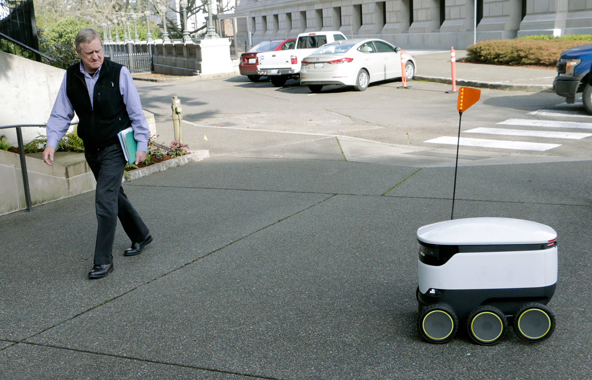 State Rep. Steve Tharinger, D-Sequim, walks by a delivery robot during a demonstration outside the Washington Capitol in Olympia on Monday. (AP Photo/Rachel La Corte)