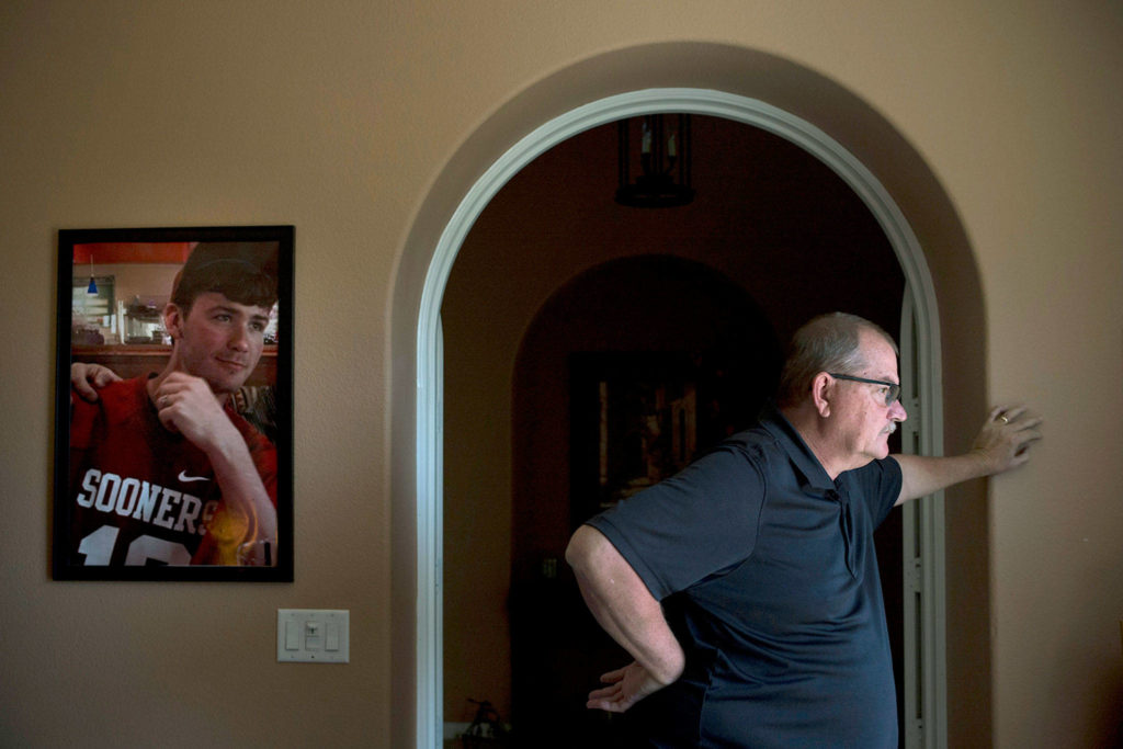 Doug Biggers, whose son, Landon, died of a heroin overdose in 2017, pauses in his home office next to a framed photo of his son wearing his favorite jersey, in La Quinta, California. (AP Photo/Jae C. Hong)
