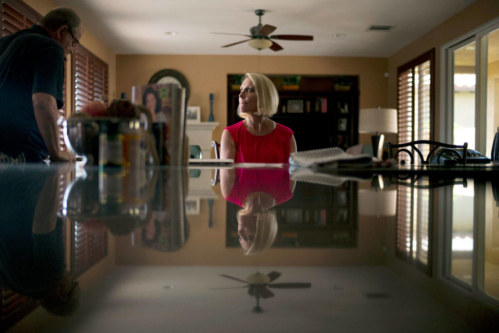 Mollie Biggers (center) looks at her husband, Doug, as he heads to his home office to take a business call in La Quinta, California. The Biggers went broke sending their son, Landon, to every type of treatment they could find, including one that promised to teach responsibility through raising a puppy. But now there isn’t much left to do but stare at the box of his ashes on a shelf above the television, hidden behind a smiling photo of the family they always wanted but never really were. The 20-year-old died of a heroin overdose in 2017. (AP Photo/Jae C. Hong) 
