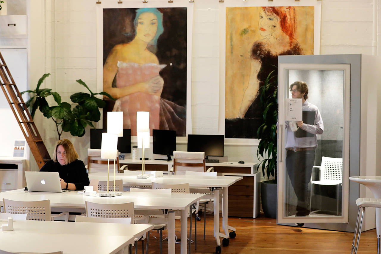 A man exits a phone conversation booth as a woman works at a table at the The Riveter, a women-focused shared workspace facility in Seattle on Jan. 11. The Riveter is one of a growing number of women-only and women-focused workspaces around the country. The Riveter has four other locations in Seattle and Los Angeles and plans to open in Austin, Texas, in March. (AP Photo/Ted S. Warren)