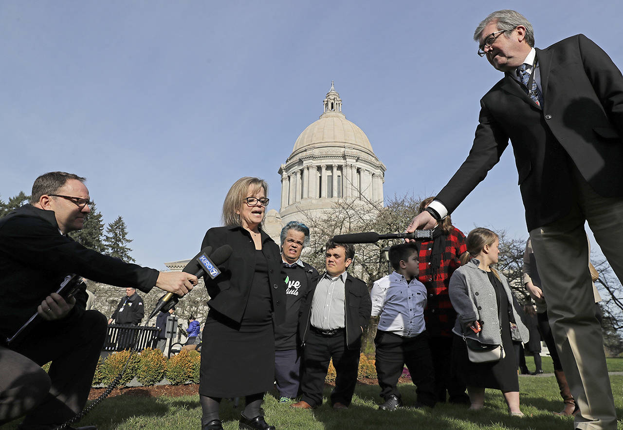 Shoshana Kehoe-Ehlers (second from left) talks to reporters Thursday at the Capitol in Olympia after a hearing before the Senate Law and Justice Committee of the Legislature to discuss a proposed statewide ban on risky entertainment events, including dwarf tossing, that feature people with dwarfism. Kehoe-Ehlers spoke in favor of the ban. (AP Photo/Ted S. Warren)