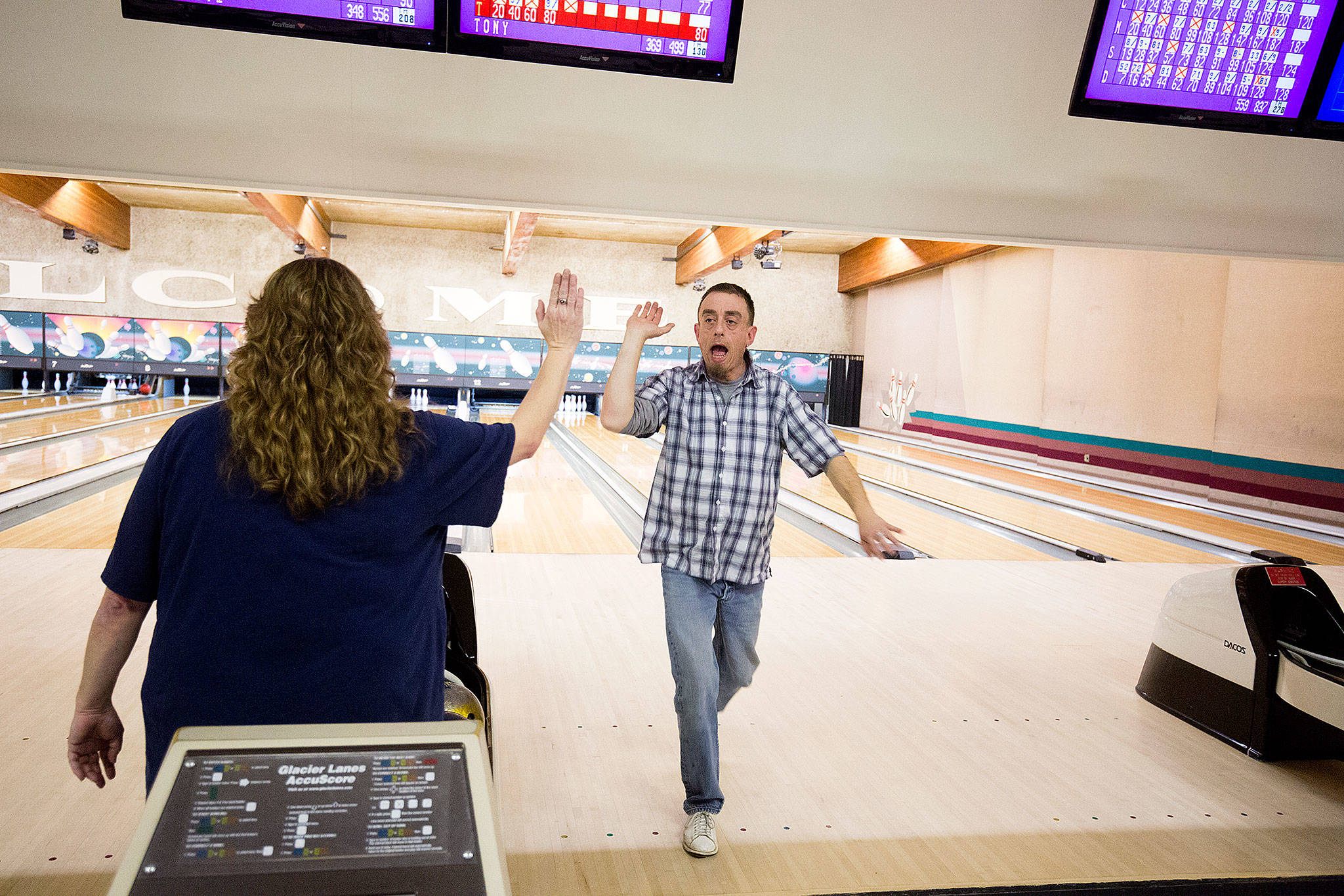 Family members Christi Aquilar high fives Tony Cea after bowling a strike at Glacier Lanes on Monday, Jan. 28, 2019 in Everett, Wa. Cea bowled a 300 recently, one of seven in his lifetime. Christie also has bowled a 300. (Andy Bronson / The Herald)