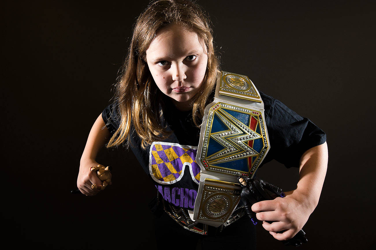 Annabelle Davis, 11, with her two championship belts, “Macho Man” Randy Savage shirt and figures of John Cena and “The Undertaker,” is an avid WWE fan. (Andy Bronson / The Herald)