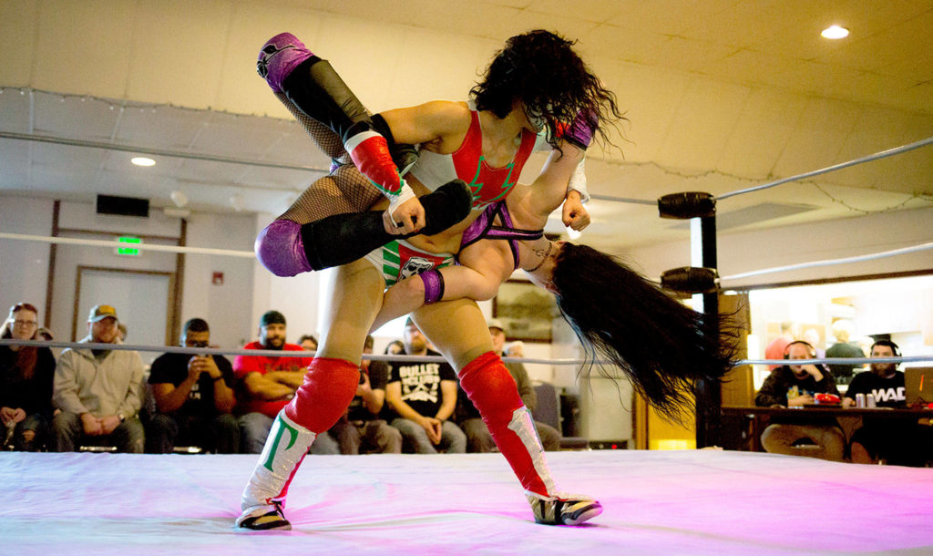 Thunder Rosa, standing, and Priscilla Kelly show off some moves in the ring at a monthly independent wrestling match at Normanna Lodge by Everett event promoter Without a Cause. (Vitz Photos)
