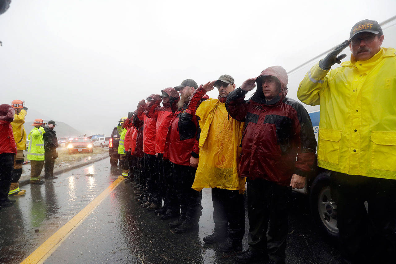 Law enforcement and other emergency personnel salute at the scene of a fatal accident where a volunteer member of the Ventura County search and rescue team was killed along Interstate Highway 5 south of Pyramid Lake, California, on Saturday. (AP Photo/Marcio Jose Sanchez)
