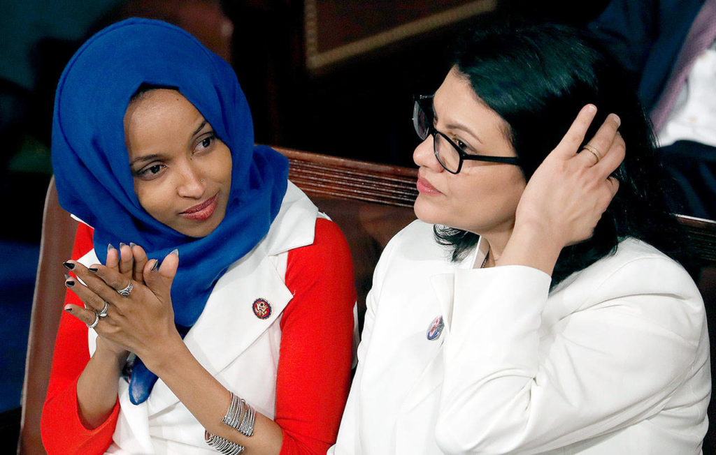 Rep. Ilhan Omar (left), D-Minn., and Rep. Rashida Tlaib, D-Mich., listen as President Donald Trump delivers his State of the Union address to a joint session of Congress on Capitol Hill in Washington on Tuesday. (AP Photo/J. Scott Applewhite) 
