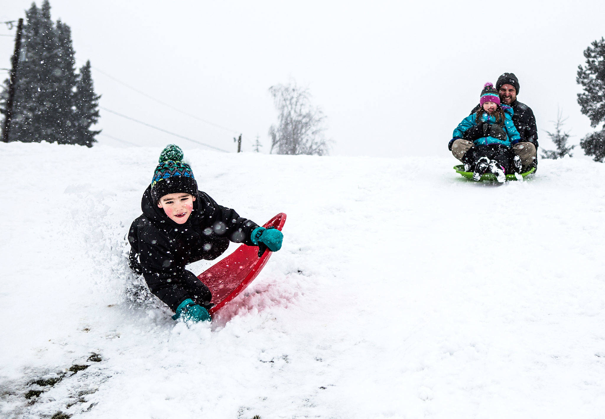 Parker Glassey, 7, left, catches air while his sister, Lola, and father, Micah Glassey, follow behind at Henry M. Jackson Park on Friday in Everett. (Olivia Vanni / The Herald)