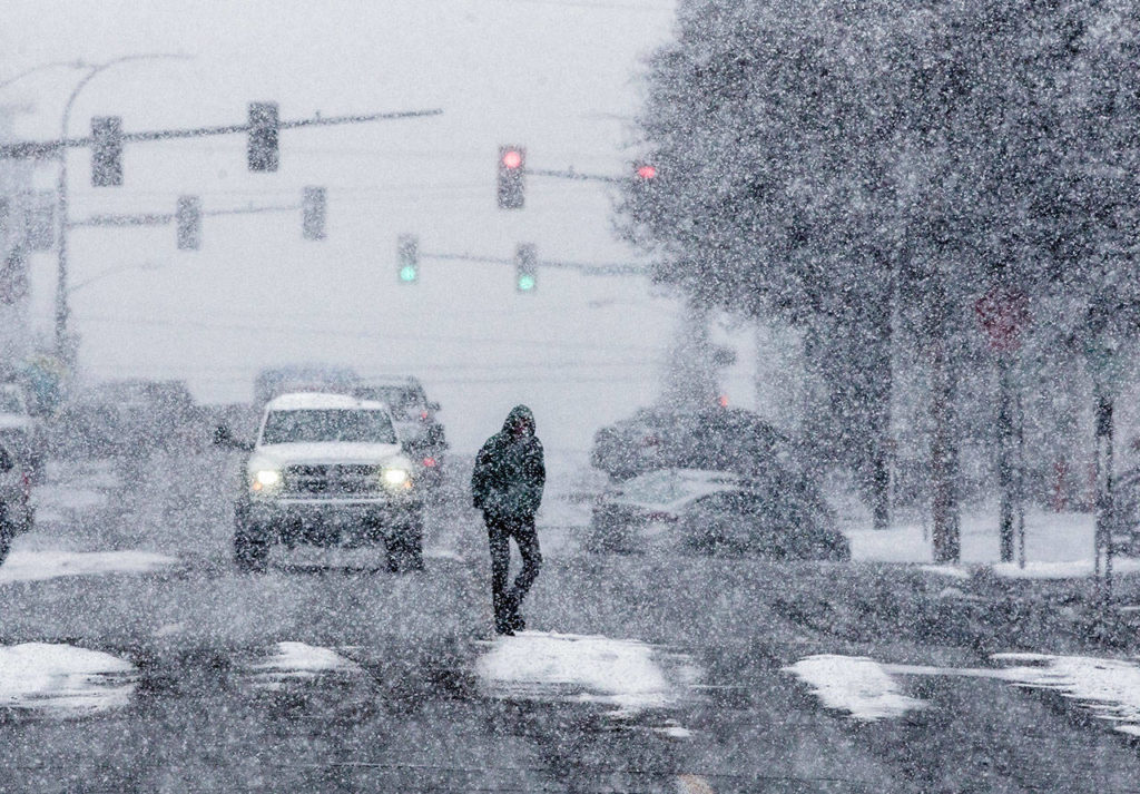 A pedestrian crosses California Street as snow begins to fall during the early afternoon on Friday in Everett. (Olivia Vanni / The Herald)
