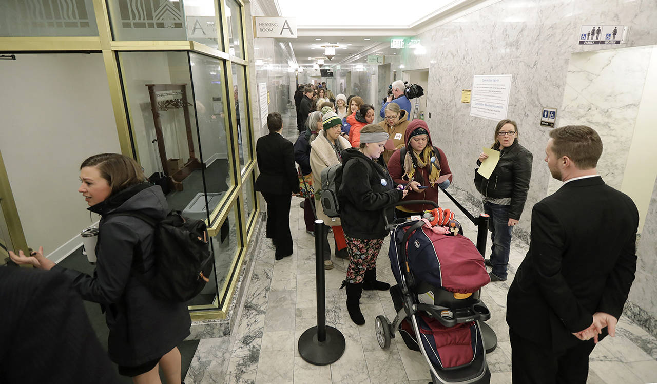 People line up in a hallway Friday before a public hearing before the House Health Care & Wellness Committee at the Capitol in Olympia. Amid a measles outbreak that has sickened people in Washington state and Oregon, lawmakers heard public testimony on a bill that would remove parents’ ability to claim a philosophical exemption to opt their school-age children out of the combined measles, mumps and rubella vaccine. (AP Photo/Ted S. Warren)