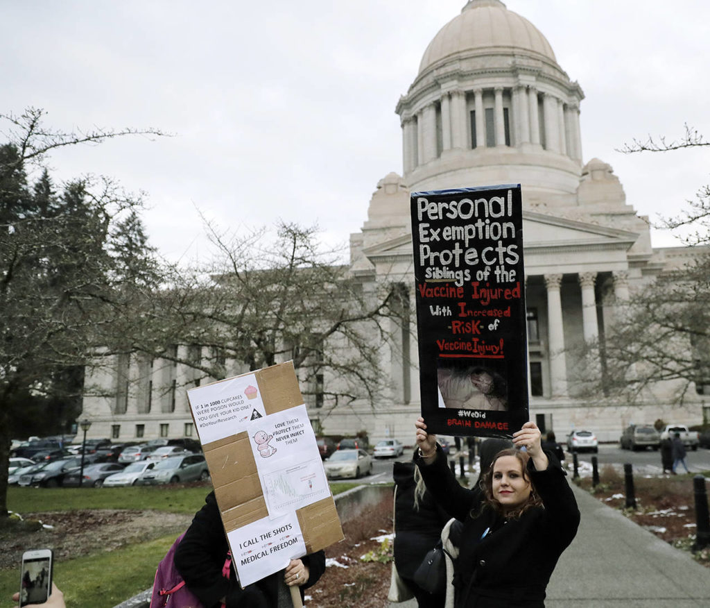 A woman holds a sign opposing a proposed bill that would remove parents’ ability to claim a philosophical exemption to opt their school-age children out of the combined measles, mumps and rubella vaccine as she stands near the Legislative Building at the Capitol in Olympia on Friday. (AP Photo/Ted S. Warren)
