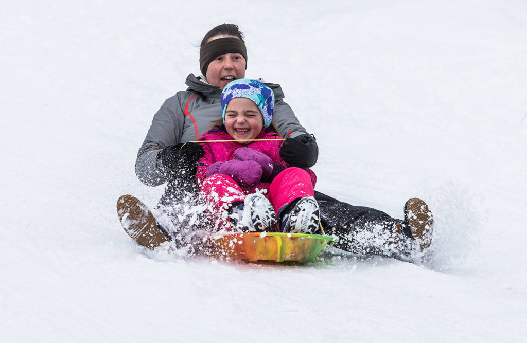 Lacey Harper sleds down a hill with daughter June Harper, 7, on Saturday in Everett. (Olivia Vanni / The Herald)
