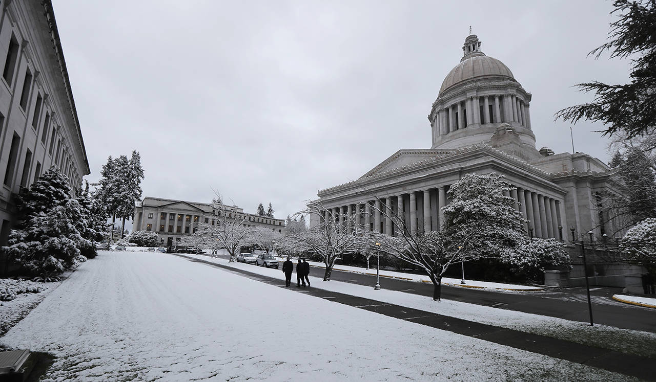 Pedestrians walk past the Legislative Building at the Capitol in Olympia on Monday. (AP Photo/Ted S. Warren)