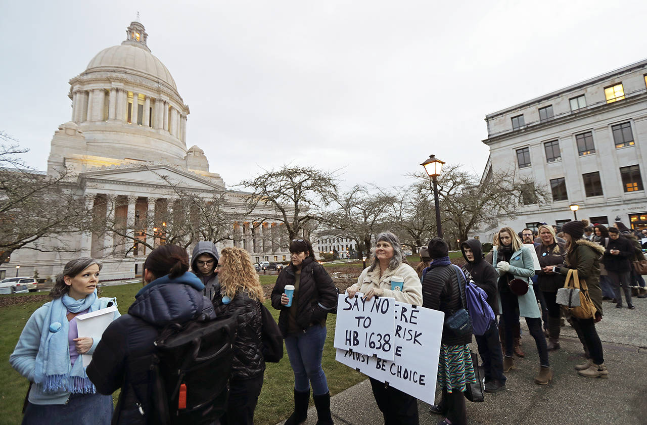 Kebby Johnson (center) of Spokane holds a sign that reads “Say No to HB 1638” as she waits in line Friday to attend a public hearing before the House Health Care & Wellness Committee at the Capitol in Olympia. (AP Photo/Ted S. Warren)